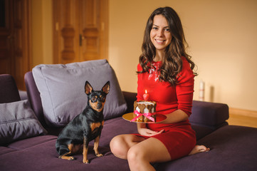 woman and toy terrier with dog cake on sofa