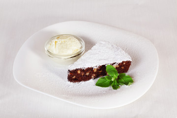 chocolate brownie cake with powdered sugar and mint plate isolated white background