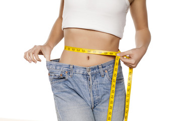 woman posing with a measuring tape and a big size pants