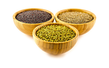 Balls of coriander seeds, jeera and mustard against white