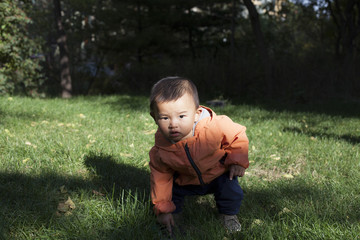 Cute Chinese baby boy studying a fountain blow hole in grass