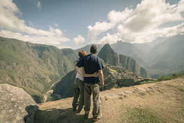 Hugging couple looking at Machu Picchu, Peru, toned image