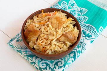 Pilaf with meat in a bowl and towel on white background