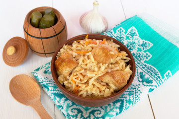 Pilaf with meat in a bowl and towel on white background
