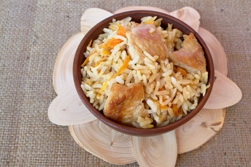 Pilaf with meat from a bowl on a wooden Board and burlap