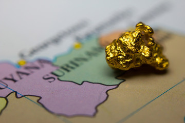 Close-up of a gold nugget on top of an old map of Suriname
