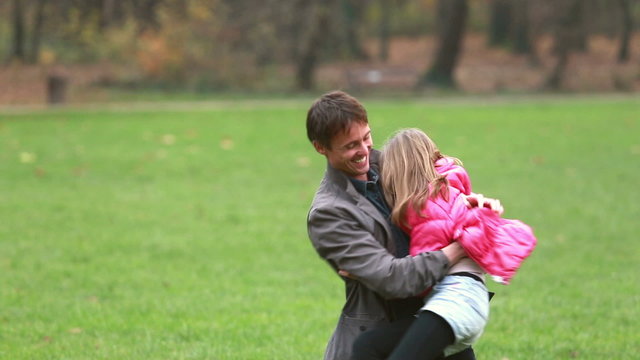 Young dad carries daughter and plays with her in park