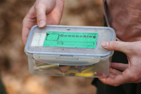 Detail of hands holding geocache found in the forest