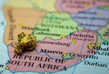 Close-up of a gold nugget on top of a map of South Africa