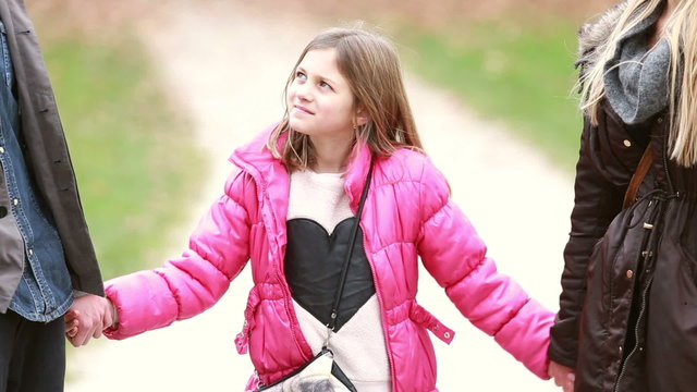 Cute little girl holding hands with parents