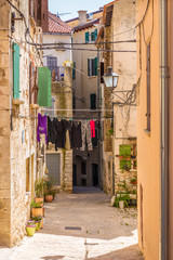 Fototapeta premium Wąska ulica z wiszącymi ubraniami - Rovinj, Chorwacja