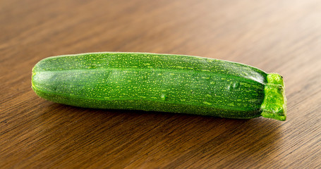Gourmet raw baby zucchini vegetable on dark wooden background