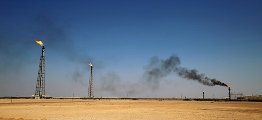 A flare stack burning off excess gas at an oil refinery in the desert of the Middle East