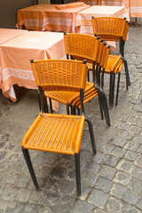 Sedie arancioni accatastate fuoti da un locale rustico di Roma