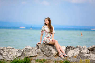 Fototapeta na wymiar Beautiful woman sitting on rock over sea