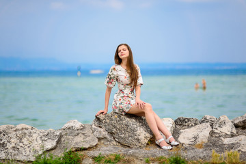 Fototapeta na wymiar Beautiful woman sitting on rock over sea