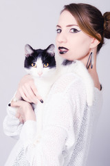 Elegant lady holding black and white cat with yellow eyes