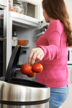 Woman Throwing Away Out Of Date Food In Refrigerator