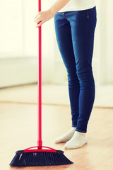 close up of woman legs with broom sweeping floor