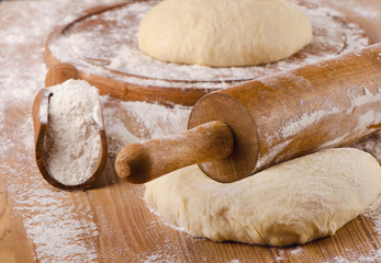 Raw Dough with rolling pin on a wooden background