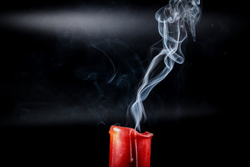gray smoke flying upside from the extinct red candles