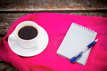 Coffee cup, notepad  and pen on wooden background