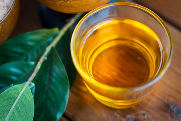 close up of honey in glass with leaves on wood