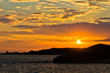 Obraz premium Picturesque cloudscape with silhouette of a sea rocks at sunset, Greece