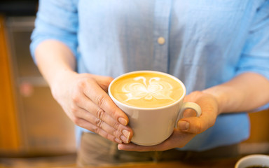 close up of hands with latte art in coffee cup