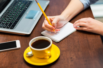 close up of woman writing to notebook with pencil