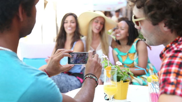 Young man taking pictures of three beautiful women
