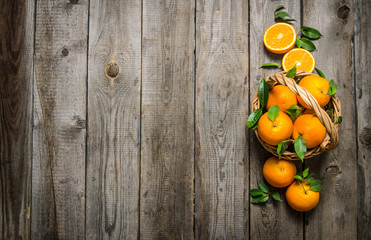 Fresh oranges in the basket with leaves.