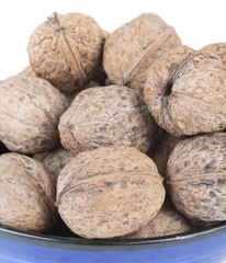 whole walnuts in blue bowl on white background