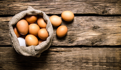 Eggs with an old bag. On wooden table.