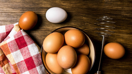 The eggs in the bowl with the whisk on the fabric.