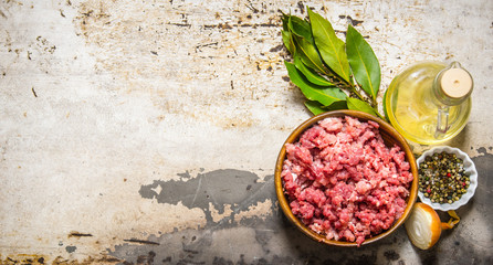 Minced meat in a wooden bowl with spices and oil.
