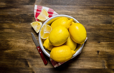 The lemons in the cup with a knife on the fabric.