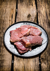 Fresh raw meat on a stand. On wooden background.