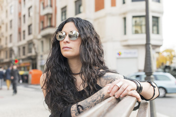 Obraz premium Fashion heavy metal style woman sitting on wood bench in the street.