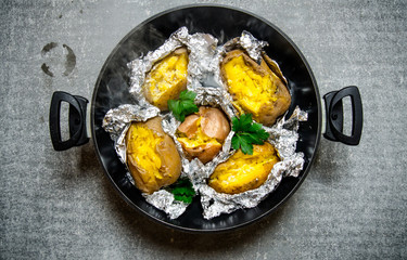 Baked potatoes in a pan on an old rustic table .