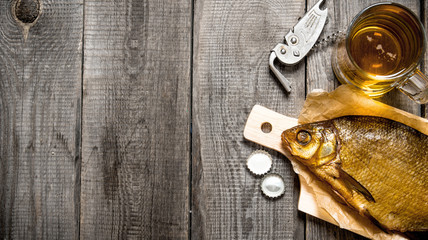 Smoked fish and fresh beer on wooden table.