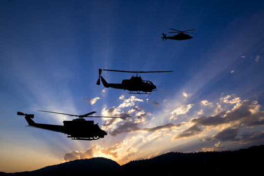 Three flying army helicopters on sunset background