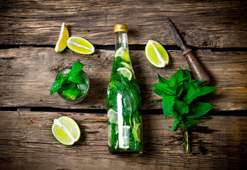 The ingredients for the cocktail - limes, mint, knife, is also prepared cocktail in the bottle and in the glass.
