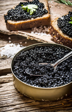 Sandwiches with black caviar, a jar of caviar and spoon.