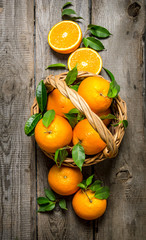 Fresh oranges in the basket with leaves.