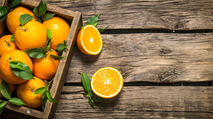 Oranges with leaves in an old box.