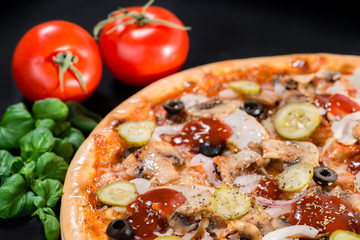 closeup Tasty pizza with tomatoes, cheese, basil and ham on a bl