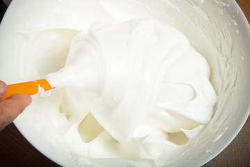 Whipped egg whites for pastry in a white ceramic bowl. Toned