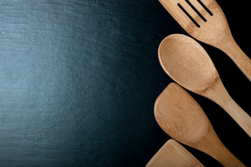Wooden cooking tools on a black background. Toned