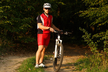 Fototapeta premium Cyclist riding mountain bike on trail at evening.